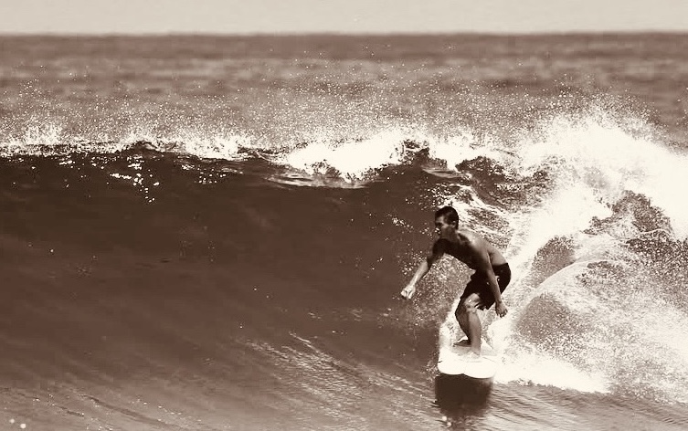 surfista sentado con vista da prancha no fondo